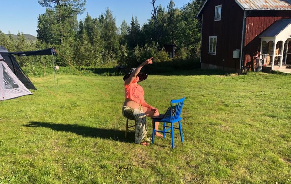 Eija Selina kesällä mökkipihalla. Talo ja teltta taustalla.