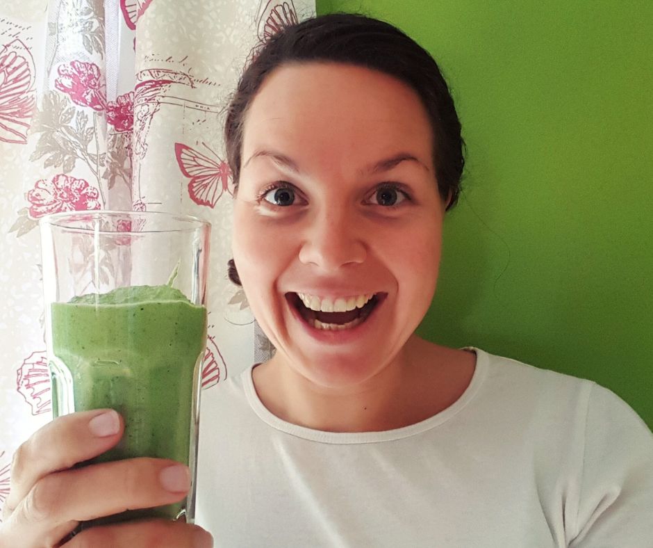 omega 3 kuvassa hymyilevä nainen jolla kädessään vihreää smoothieta lasissa